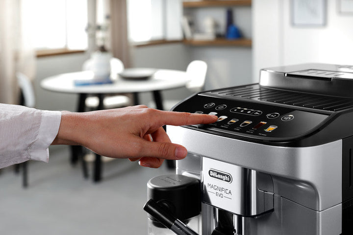 Detalle del panel táctil de la cafetera DeLonghi Magnifica Evo ECAM29084SB seleccionando una bebida en una cocina moderna