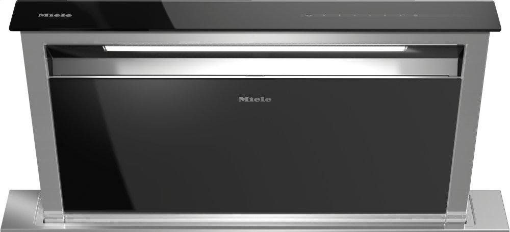 Campana extractora downdraft Miele DA 6891 de 36 pulgadas elevada sobre la encimera, en vidrio negro con marco de acero inoxidable y wordmark Miele