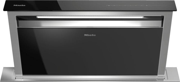 Campana extractora downdraft Miele DA 6891 de 36 pulgadas elevada sobre la encimera, en vidrio negro con marco de acero inoxidable y wordmark Miele