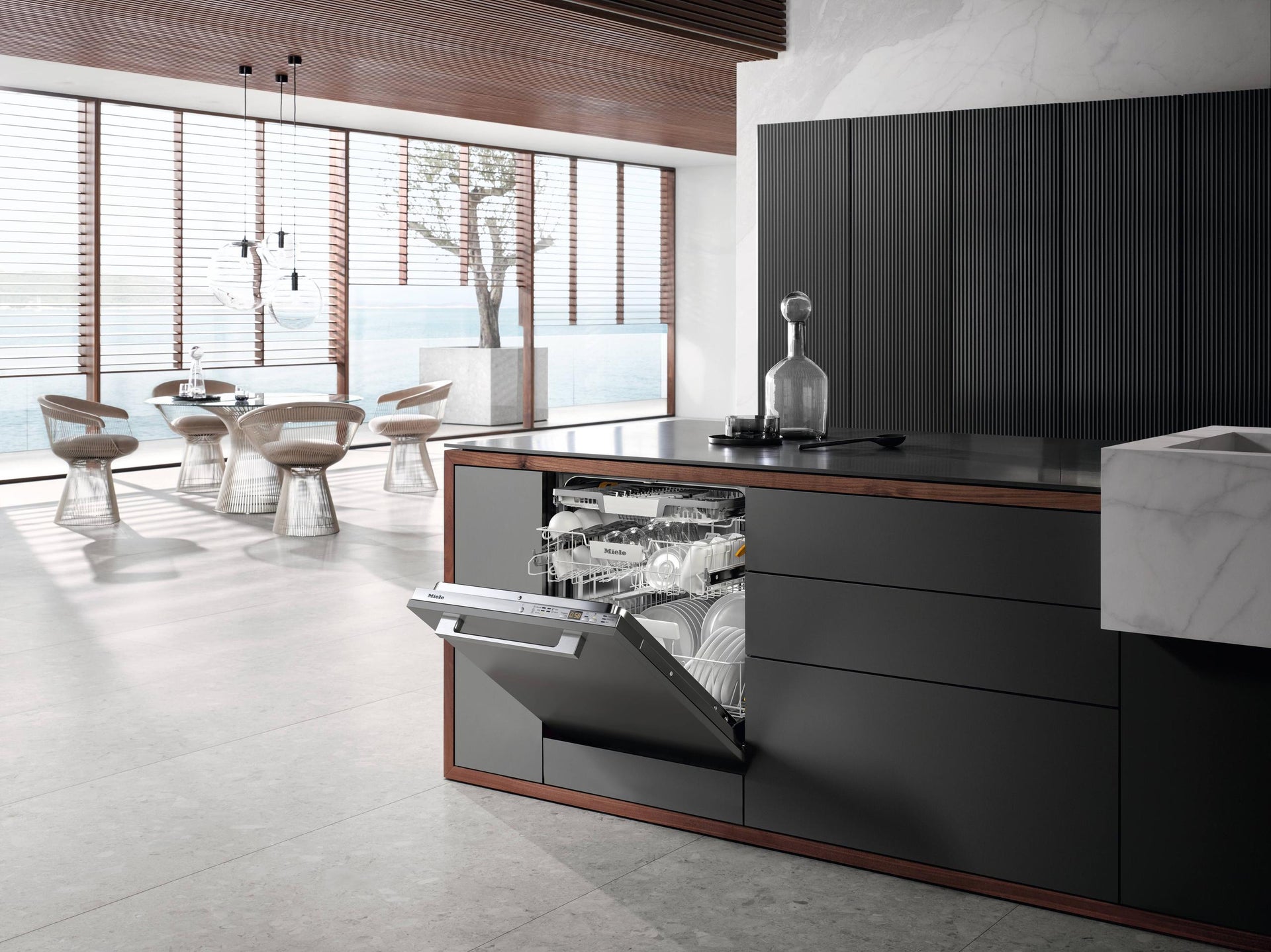 Lavavajillas Miele G 5266 SCVi integrado en isla oscura de cocina de lujo con puerta entreabierta y vista al mar