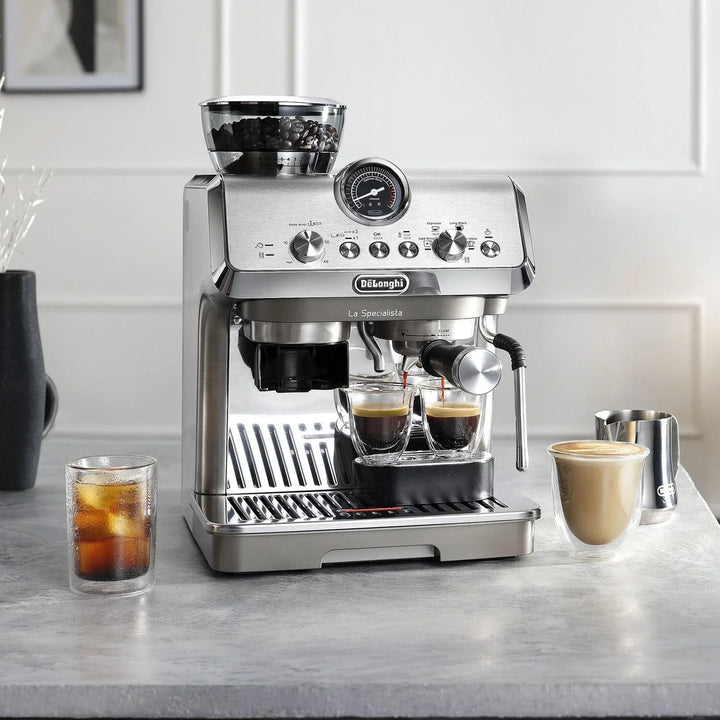 Cafetera espresso DeLonghi La Specialista EC9255M sirviendo café junto a un vaso de café frío